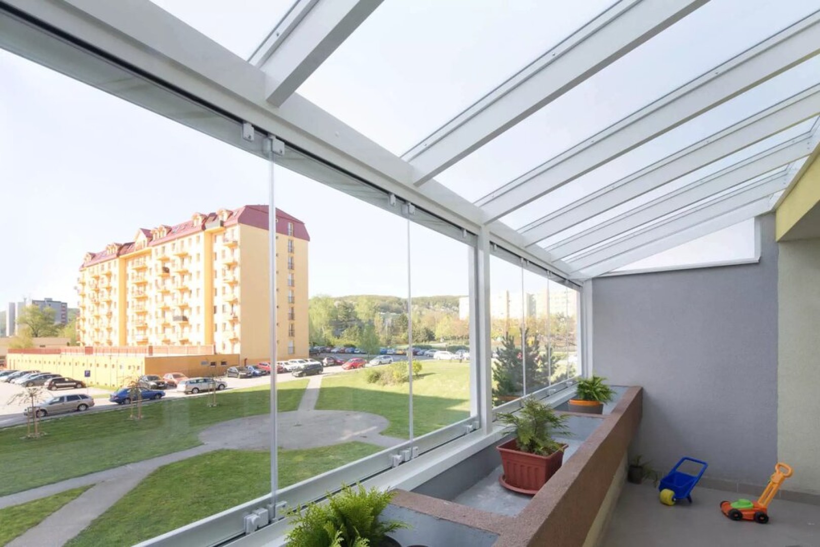Modern, keret nélküli erkélyüvegezés, kilátással a lakótelepre és a zöldterületekre