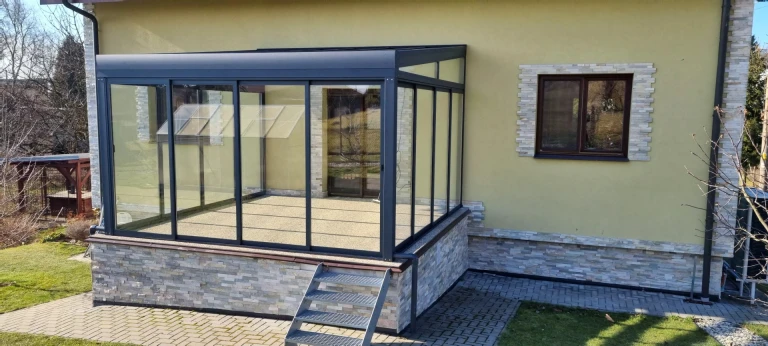 A családi házhoz csatlakozó, lépcsővel ellátott, üvegezett ROBUST alumínium pergola