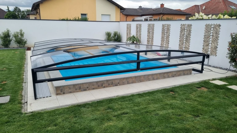 Modern, alacsony medencefedés fekete vázszerkezettel és átlátszó burkolattal a kertben