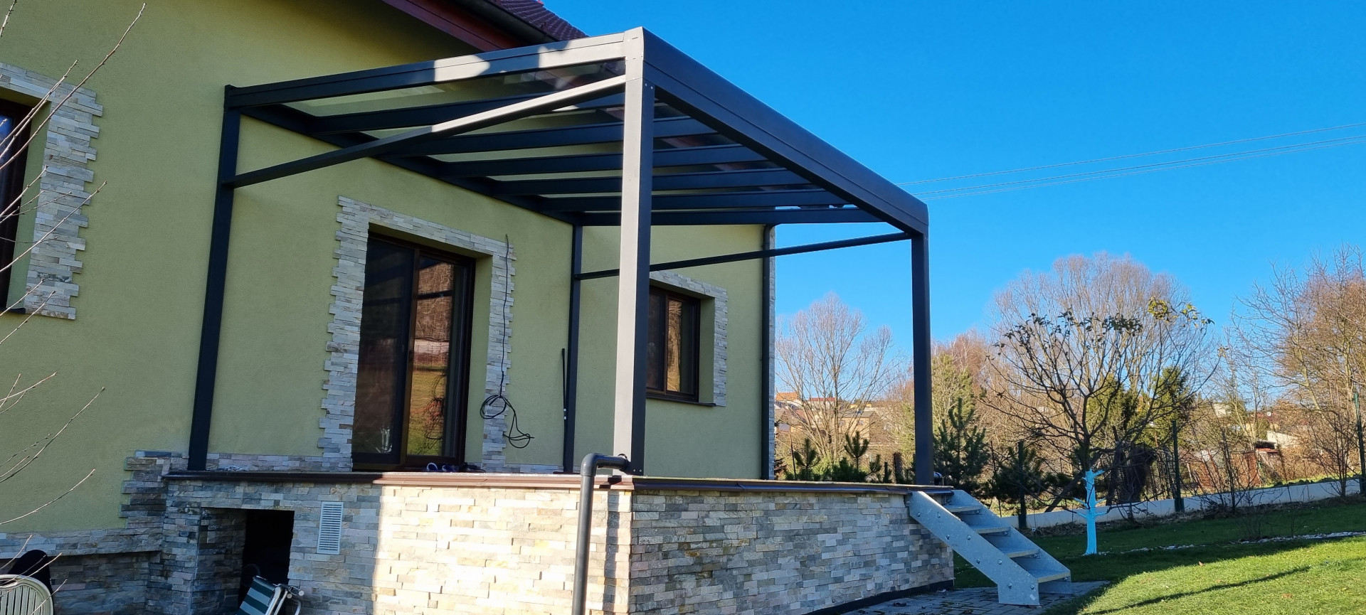 A ROBUST modern, sötét szürke alumínium pergola üvegtetővel, egy családi ház teraszára felszerelve.