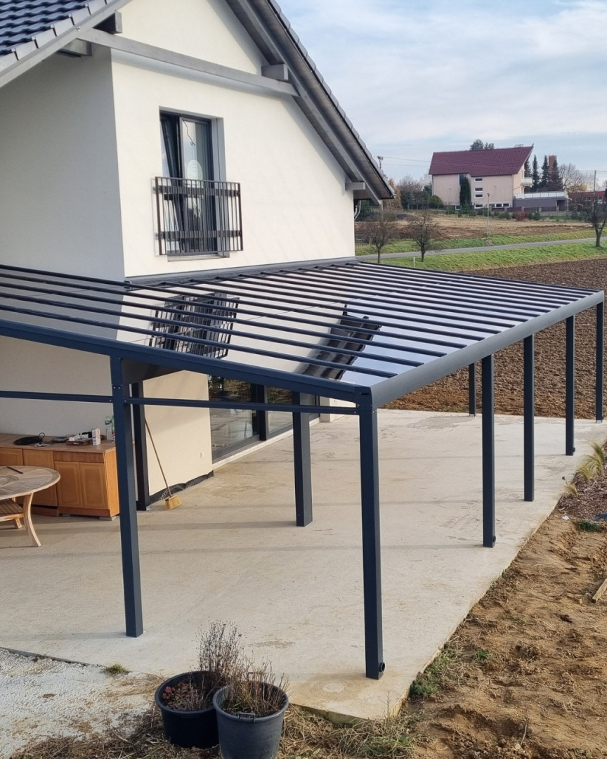 Modern, sötét szürke alumínium pergola üvegtetővel, amelyet egy családi házhoz szereltek fel Sencben.