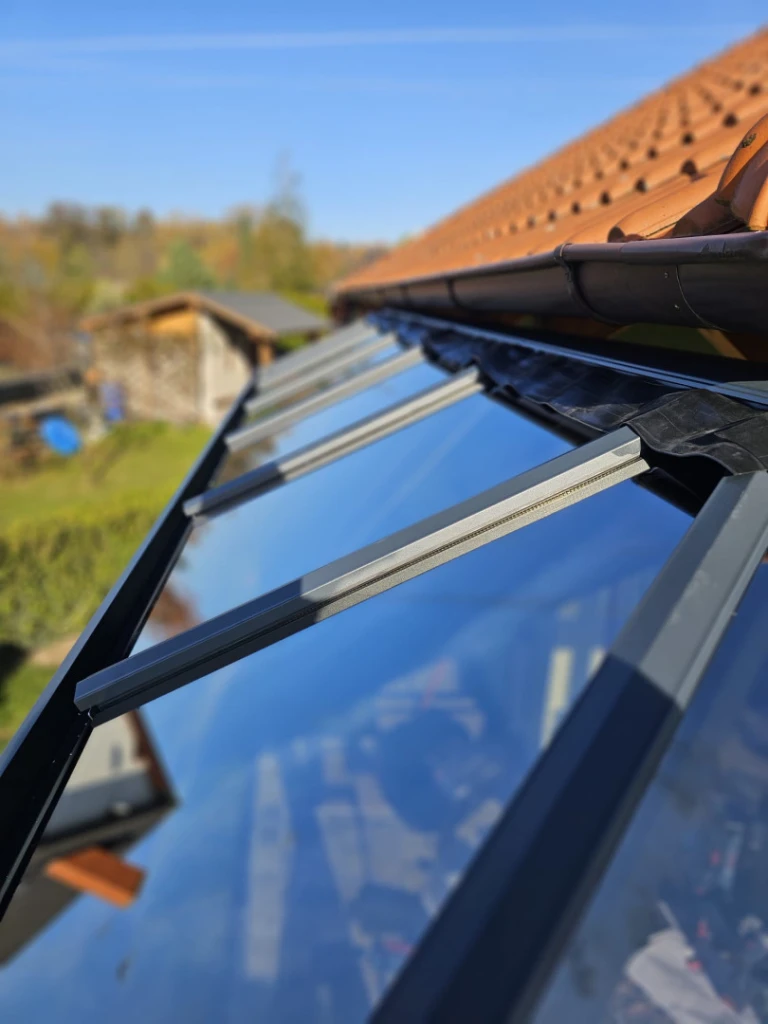 A pergola üvegezett tetőszerkezetének a ház falához, az eresz alatt történő csatlakozásának részlete