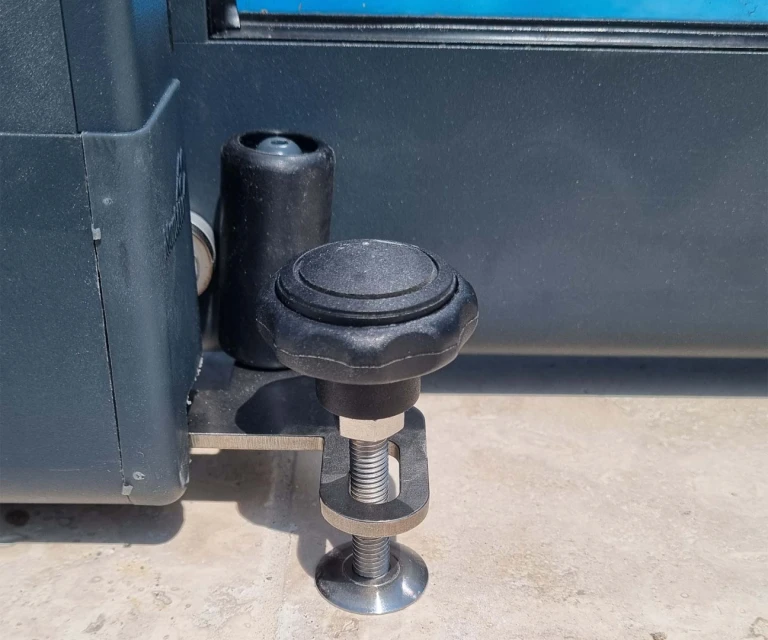 Részletes képet adunk a medencefedél rögzítőmechanizmusáról és rögzítőcsavarjáról a burkolaton.
