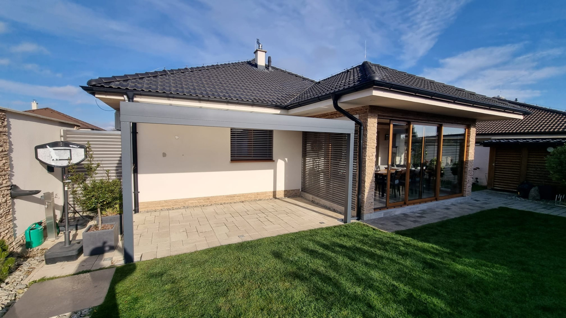 Modern, szürke alumínium pergola a bungaló mellett, a kert melletti burkolt teraszon