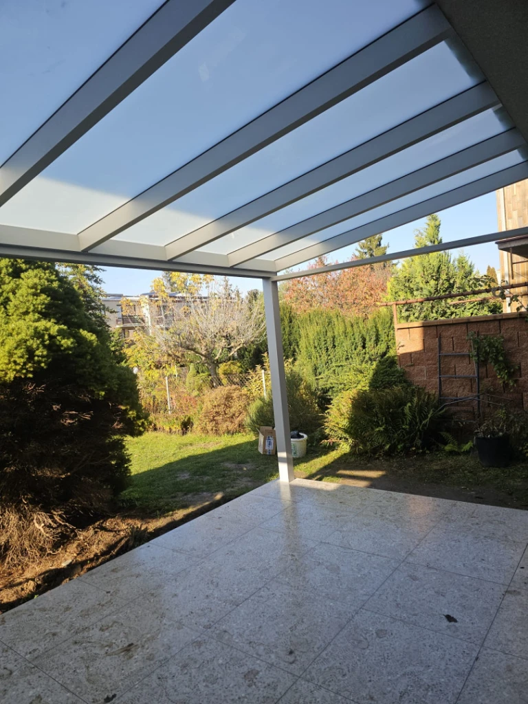 Modern alumínium pergola üvegtetővel a terasz felett, kilátással a kertre