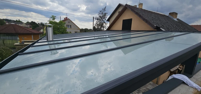 Felülnézet a családi ház melletti, sötét vázszerkezetű, modern télikert üvegtetőjére