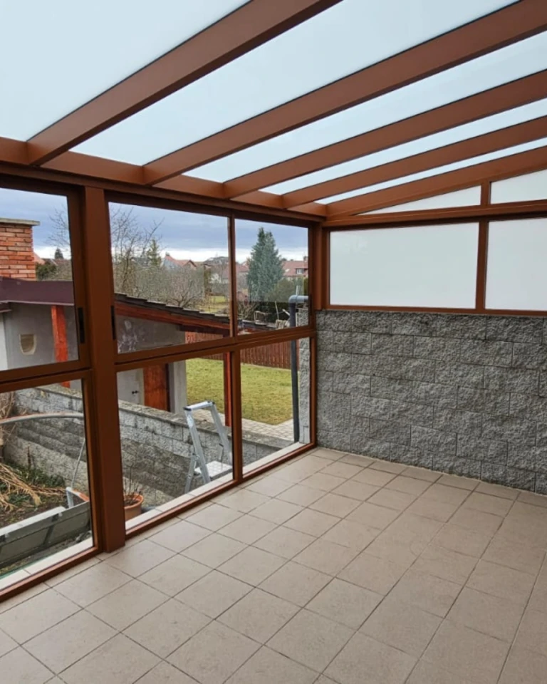 Üvegezett alumínium pergola barna vázszerkezettel és kilátással a kertre